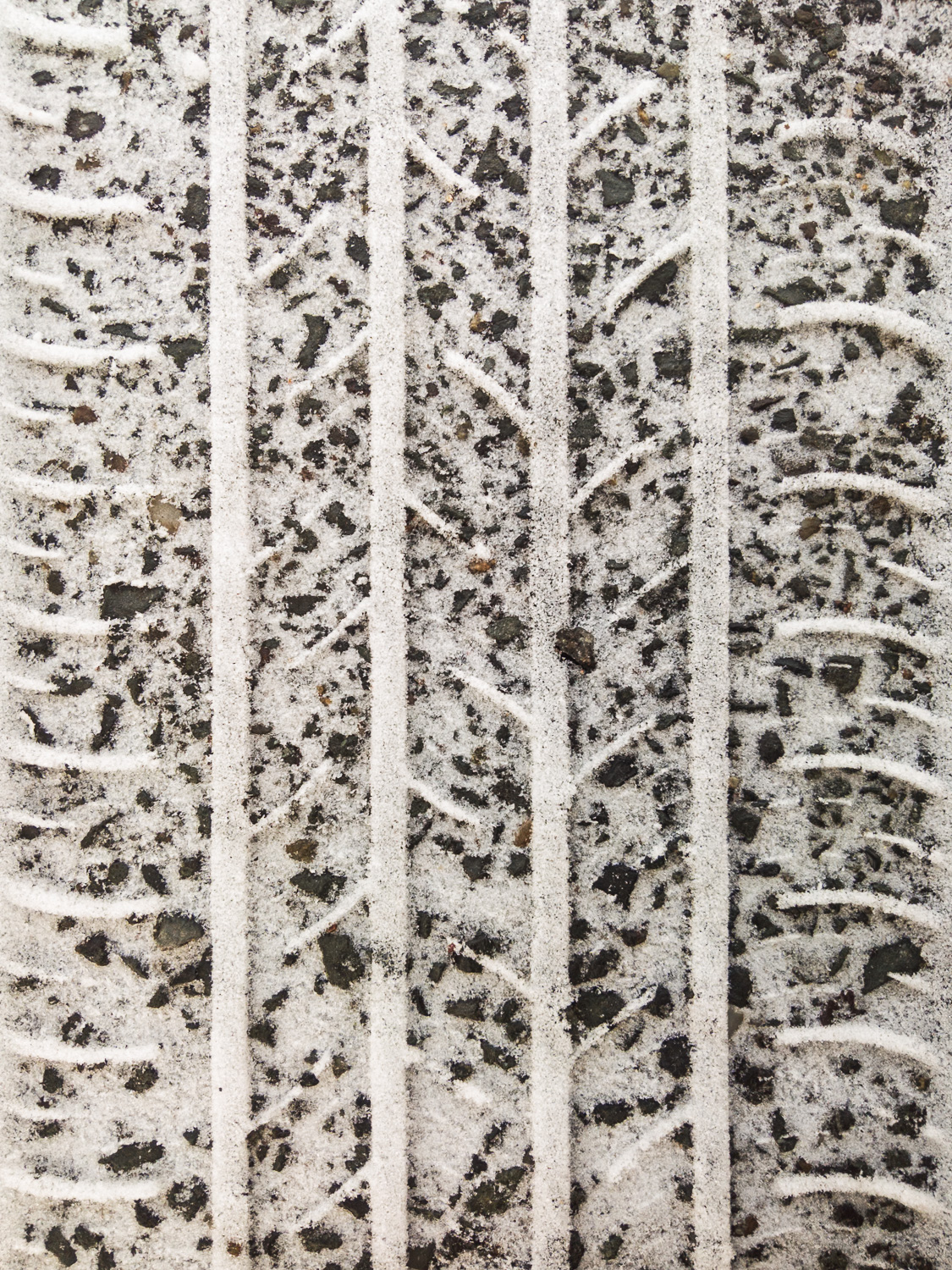 Photo of tire tracks left behind in snow over asphalt